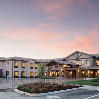 A hotel building at sunset with a clear view of the parking lot in front.