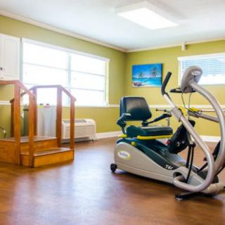 A well-lit rehabilitation room featuring an exercise bike and wooden steps.