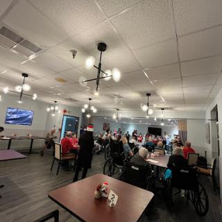 A community gathering space filled with individuals in wheelchairs, enjoying an event under warm lighting.