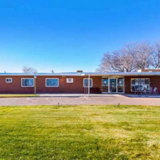 A small brick motel building with a grassy lawn and clear blue sky.