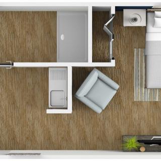 A top-down view of a bedroom floor plan featuring a bed, an armchair, and an adjacent bathroom.