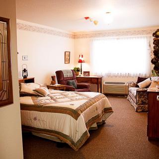 A cozy bedroom with a bed, desk, and window letting in natural light.