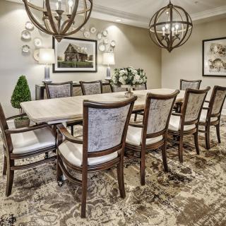 A beautifully decorated dining room with a long table, elegant chairs, and ornate chandeliers.