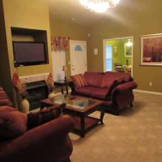 A cozy living room with sofas, a coffee table, and a television mounted above the fireplace.
