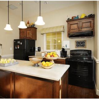 A modern kitchen with wooden cabinets, black appliances, and a central island adorned with fruit bowls.
