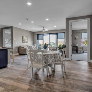 A modern dining area with an open layout, featuring wooden flooring and ample natural light.