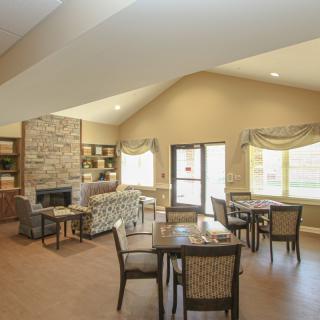 A cozy living room with a fireplace, dining tables, and comfortable seating.