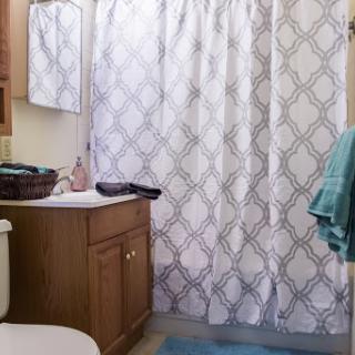A cozy bathroom featuring a patterned shower curtain and neatly arranged towels.