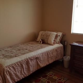 A cozy bedroom with a single bed, dresser, and window.