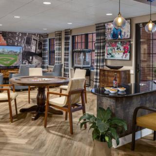 A stylish interior room with a round table, chairs, and decorated walls featuring artwork and pendant lighting.