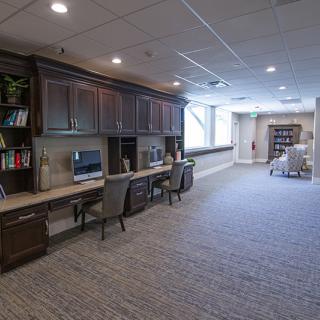 A spacious and modern office workspace with desks, computers, and a bookshelf.
