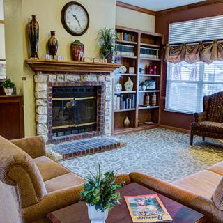 A cozy living room featuring a fireplace, bookshelf, and comfortable seating.