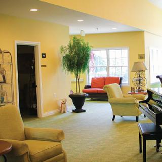 A cozy living room with comfortable seating, a piano, and large windows letting in natural light.