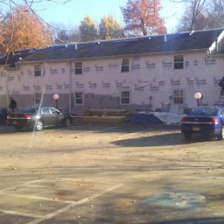 A view of an apartment building with vehicles parked in front and construction materials visible.