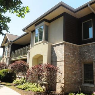 A modern two-story residential building with a stone facade and well-maintained landscaping.