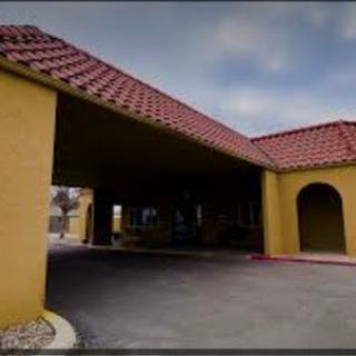 A view of the entrance to a hotel with yellow walls and a red tile roof.