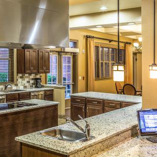A modern kitchen with granite countertops, stainless steel appliances, and warm lighting.