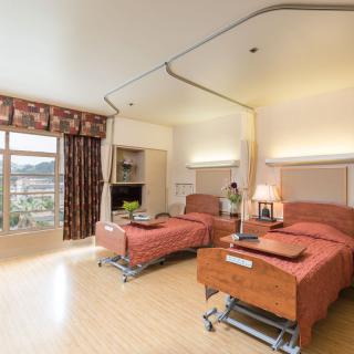 A well-lit hospital room with two patient beds and a view of the outdoors.