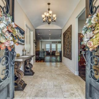 Elegant entryway with decorative flowers and a chandelier leading into a welcoming home.