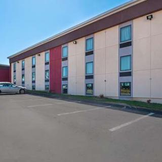 A view of a hotel building with a parking lot in front.