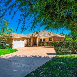 A beautiful suburban house with a driveway and a well-maintained lawn on a sunny day.