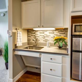 A modern, compact kitchen area featuring a sink, stainless steel appliances, and decorative backsplash tiles.