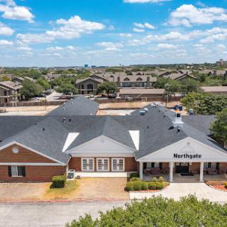 Aerial view of a residential building in a suburban setting, showcasing its architecture against a backdrop of blue skies.