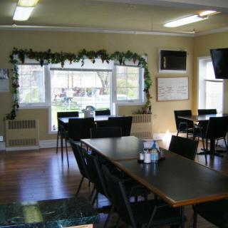 A cozy dining area with tables, chairs, and a decorated window.