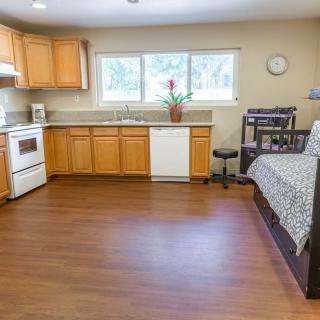 A cozy kitchen with wooden cabinets, a stove, and a sofa on hardwood flooring.