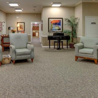 A cozy lobby area featuring comfortable chairs, a piano, and decorative artwork on the walls.