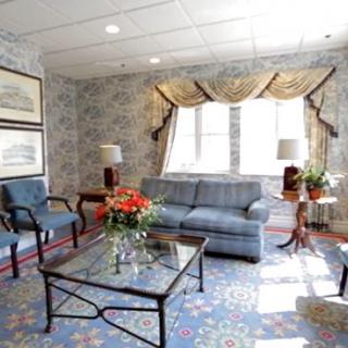 A cozy living room with a floral-patterned carpet, blue sofa, and elegant decor.