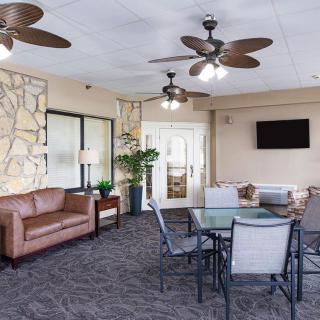 A cozy lounge area with comfortable seating, ceiling fans, and a mounted television.