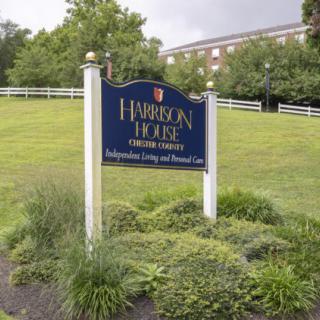A sign for Harborside Healthcare Hamilton House Center stands in a grassy area with a building in the background.