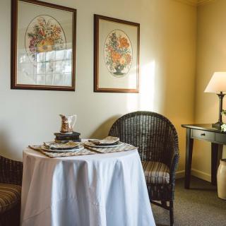 A cozy dining nook with a round table, wicker chairs, and framed artwork.
