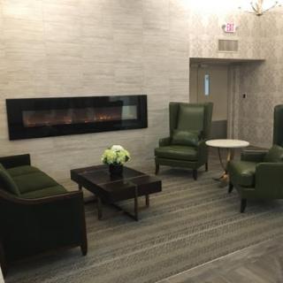 A cozy lobby area featuring green armchairs and a modern fireplace.