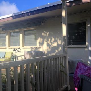 A cozy house exterior with a balcony, featuring a window and some outdoor furniture.