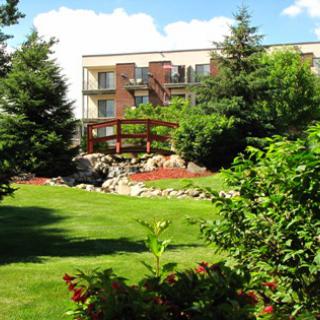 A serene outdoor scene featuring a well-maintained garden with lush greenery and a wooden bridge.