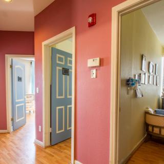 A colorful hallway with multiple doors leading to different rooms, one of which appears to be a nursery.