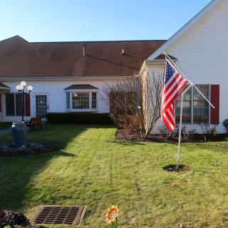 A residential yard with a well-maintained lawn and an American flag displayed on a pole.