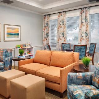 A cozy living room with a peach sofa, patterned curtains, and colorful decor.