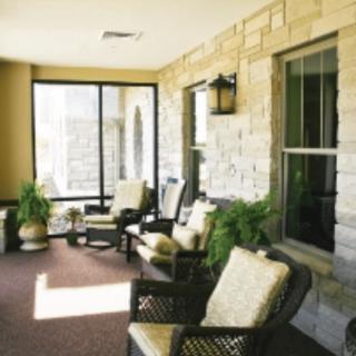 A cozy patio area with comfortable seating and potted plants against a stone wall.