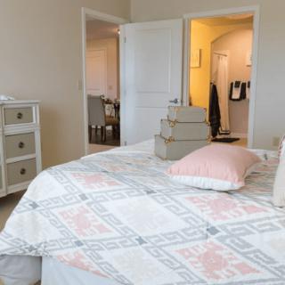 A cozy bedroom featuring a bed with a patterned duvet and pillows, accompanied by a dresser in the corner.