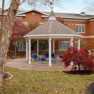 A picturesque outdoor gazebo surrounded by autumnal trees and seating.