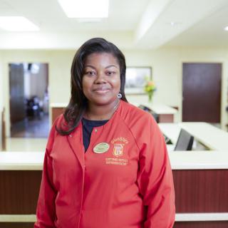 A professional in a red jacket stands in a reception area.