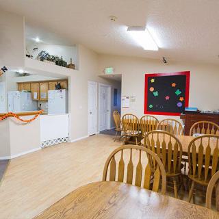 A well-lit dining area with multiple wooden tables and chairs, featuring decorative elements on the walls.