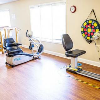 A bright exercise room equipped with stationary bikes and rehabilitation tools.