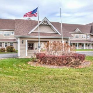A large building with an American flag flying in front, featuring well-maintained landscaping and a cloudy sky above.