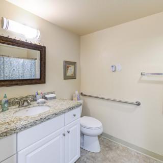 A clean and simple bathroom with a granite countertop and white cabinetry.
