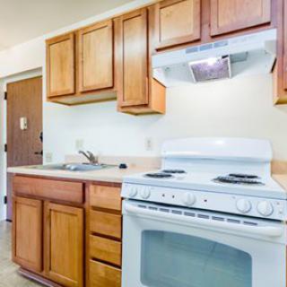 A small kitchen with wooden cabinets, a white stove, and a sink.