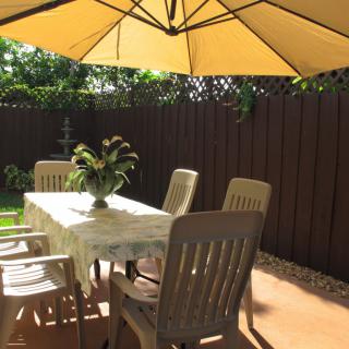 A sunny outdoor patio with a table, chairs, and a large umbrella.